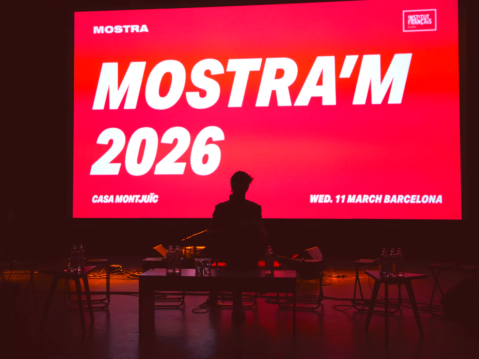 Obertura de Mostra'm 2026 a Casa Montjuïc: un ponent a l'escenari davant la pantalla vermella